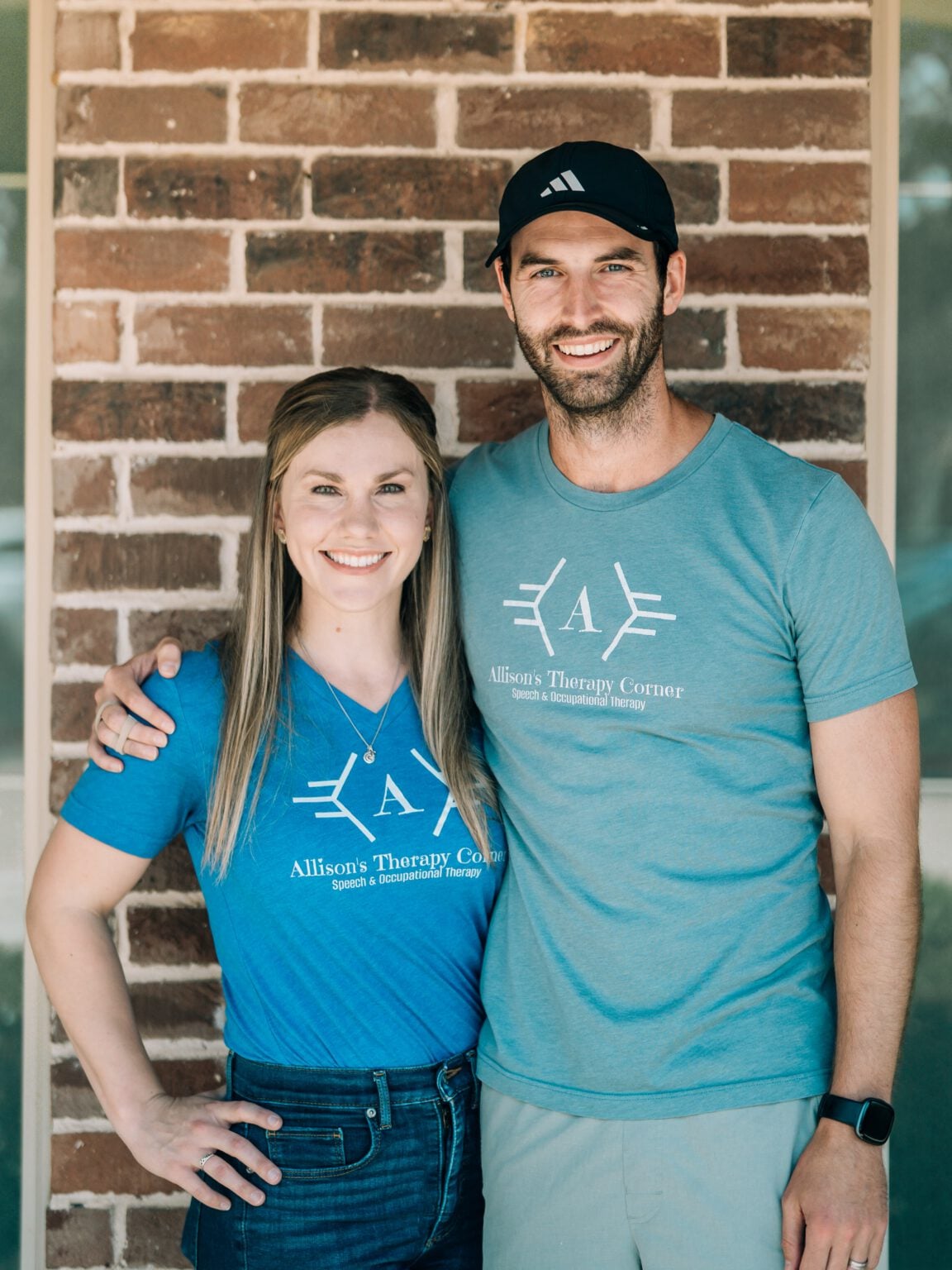 Owners of Allison’s Therapy Corner standing together wearing branded shirts outside the clinic.