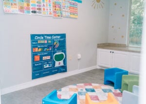 A bright circle time room with small chairs, learning posters, and a colorful rug ready for group activities.