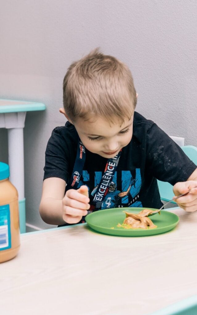 Young boy practicing feeding therapy with peanut butter at pediatric clinic.