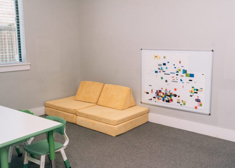 Autism therapy room with seating area and whiteboard at Allison’s Therapy Corner.