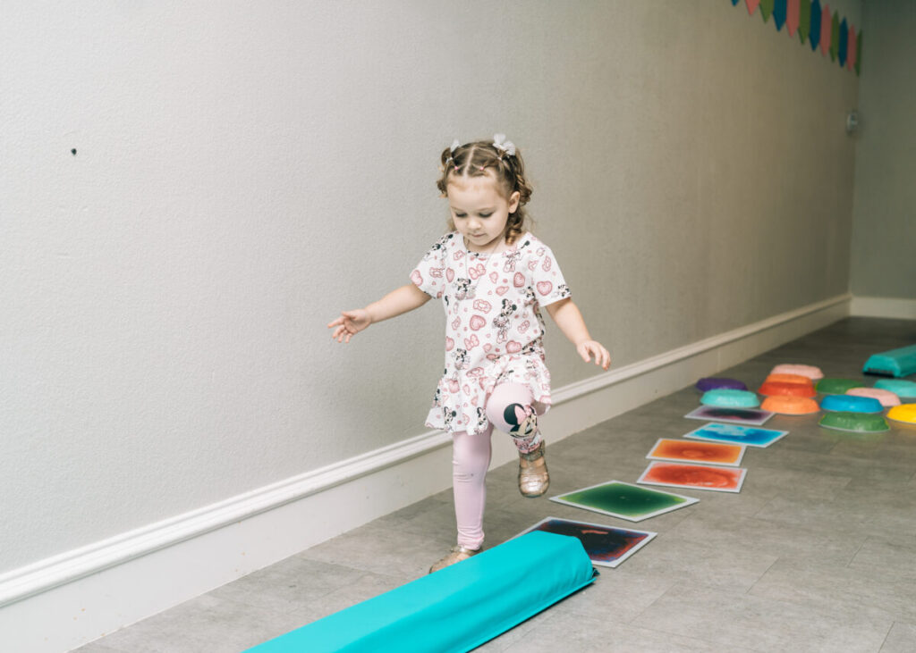 Child practicing balance on sensory path during occupational therapy session.