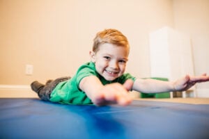 Child practicing motor coordination and strength during occupational therapy session.