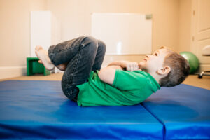 Child working on core strength and motor control during occupational therapy exercises.