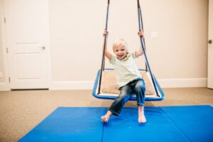 Child enjoying sensory swing therapy activity for balance and coordination.