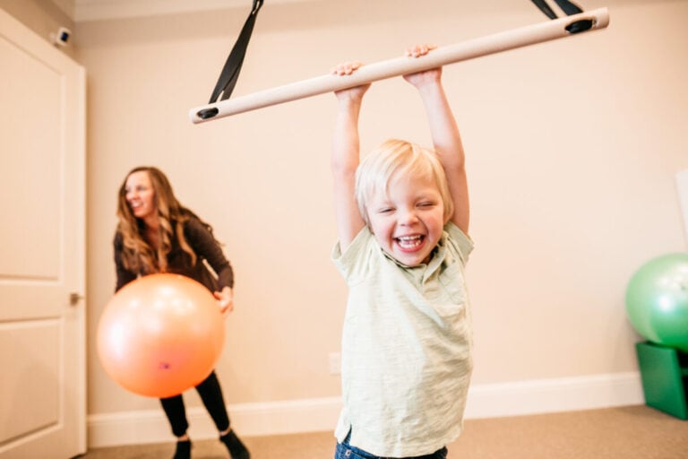 Child doing occupational therapy sensory activity with therapist support in Keller TX clinic.