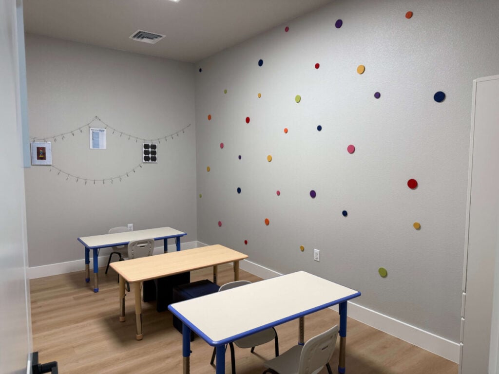 ABA therapy classroom with colorful wall dots and student work tables
