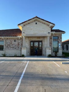 Exterior entrance of ABA therapy clinic in Fort Worth with staff member standing at front door.